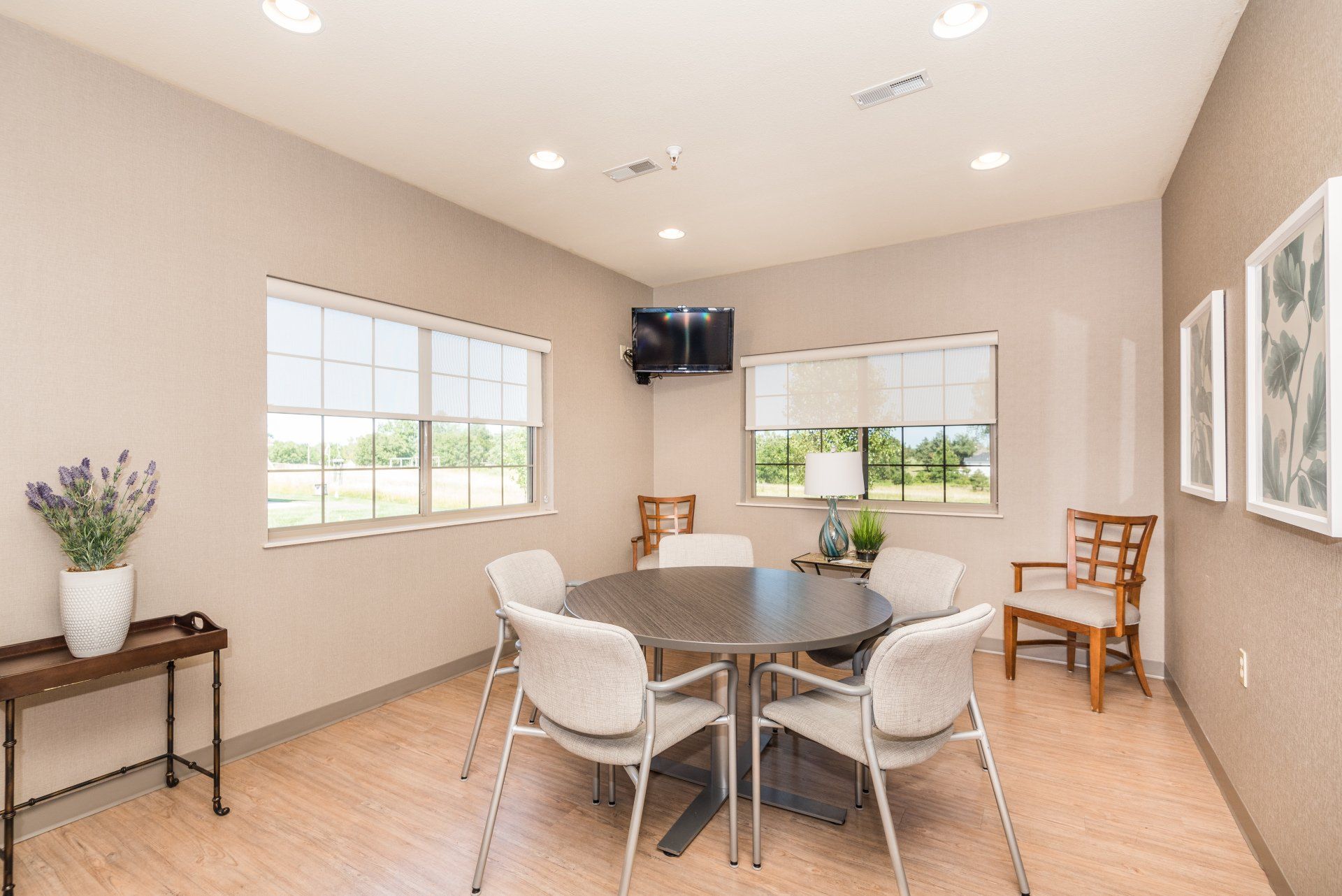 A room with a table and chairs and a television on the wall.