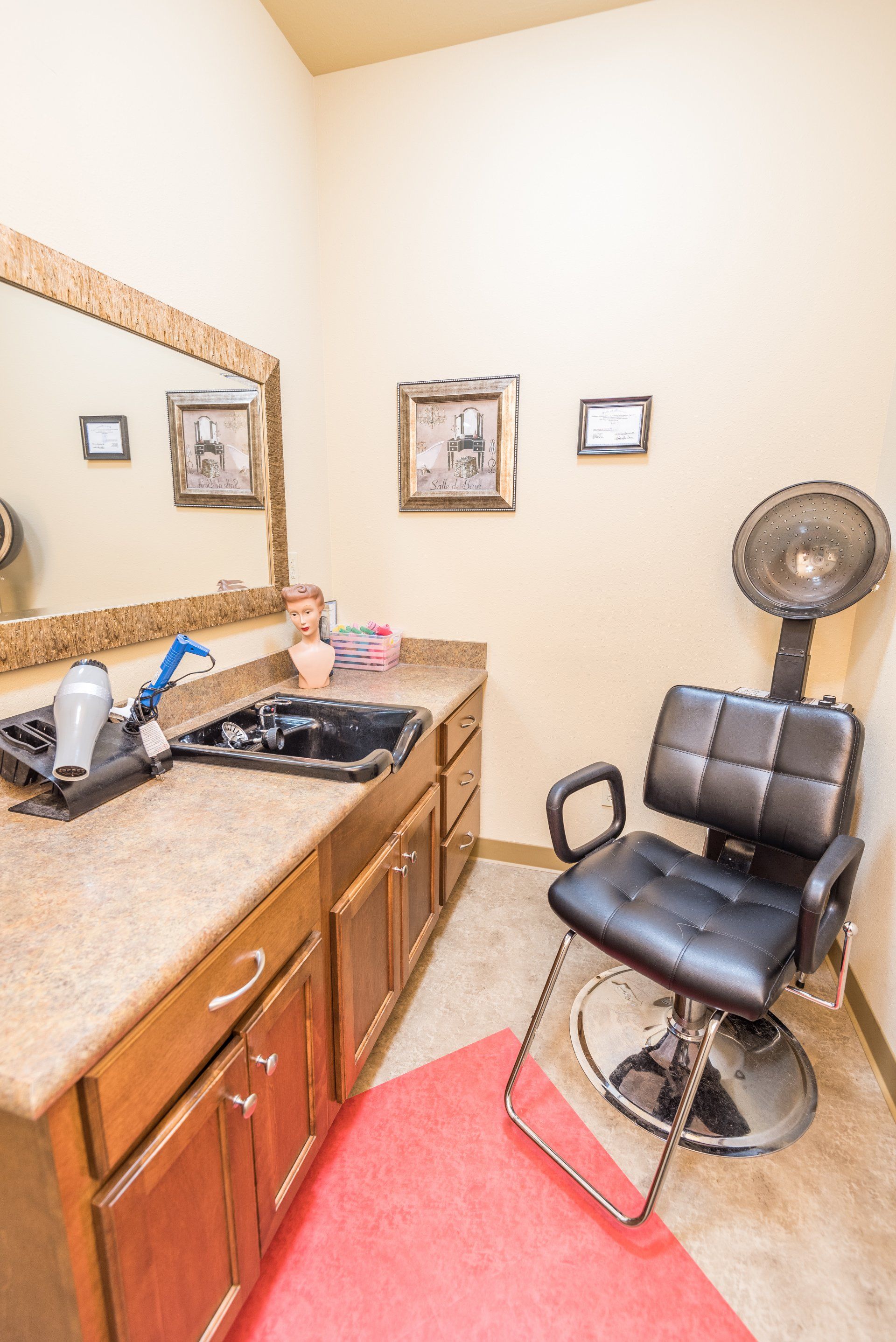 A hair salon with a chair , sink , mirror and dryer.