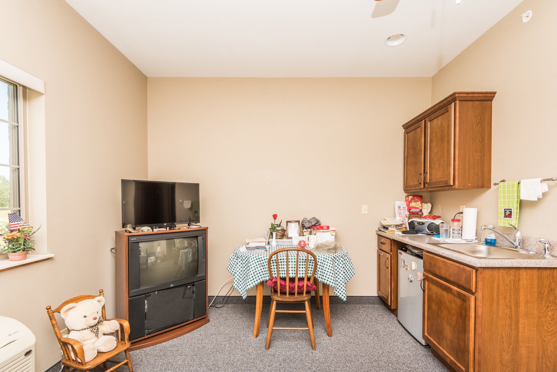 A living room with a table and chairs , a television , and a kitchen.