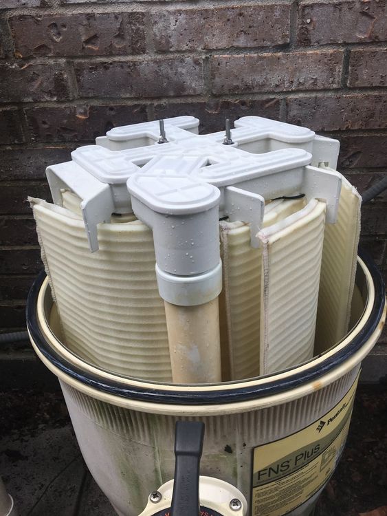 Pool filter with circular pleated filter elements inside a cylindrical container.