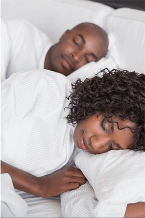 A man and a woman are sleeping on a bed