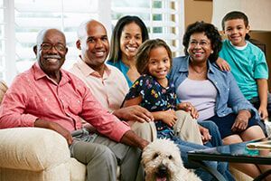 A large family is sitting on a couch with a dog.