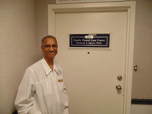 A man in a lab coat is standing in front of a door.