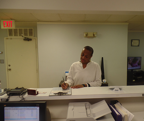 A woman is sitting at a desk in front of an exit sign