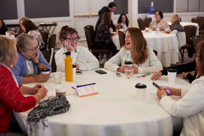 HECA members smiling and talking around at table