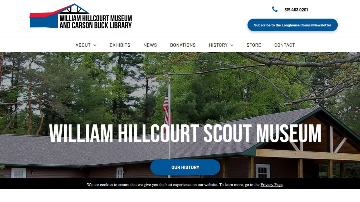 The william hillcourt scout museum website shows a picture of a log cabin surrounded by trees.