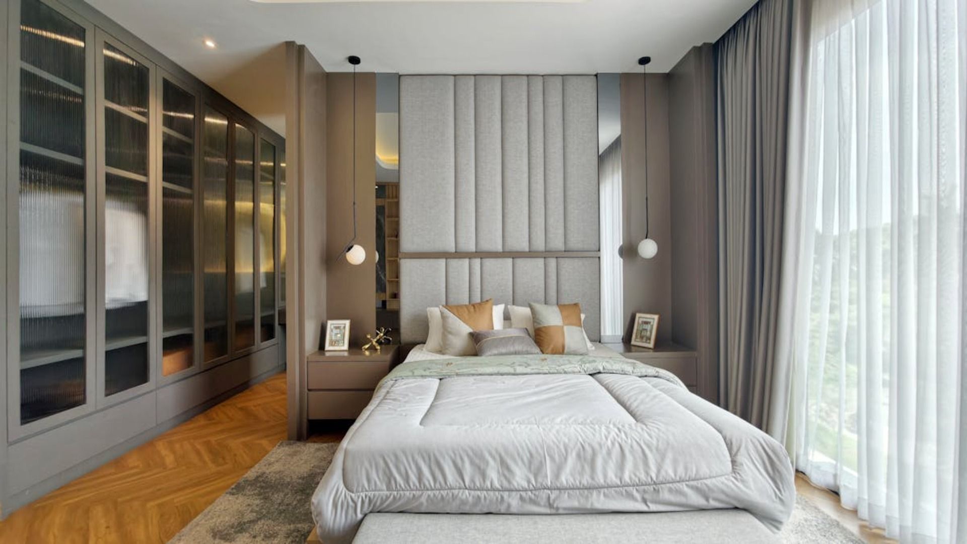 Dormitorio con decoración en tonos grises y beige, vestidor y cama con amplio cabecero.