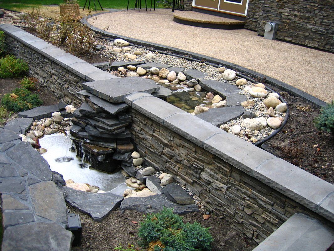 A beautiful French drain system with retaining wall and waterfall for residential back yard in Victoria BC