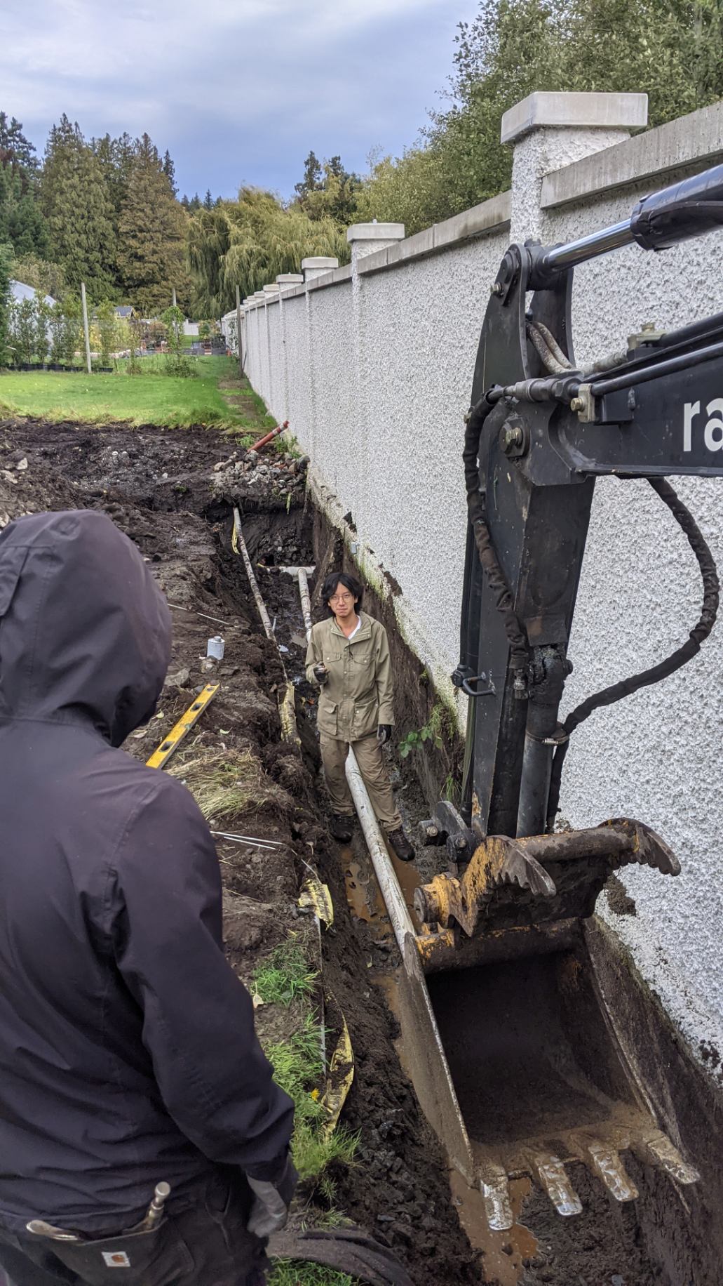A mini excavator digging a trench for a perimeter drain system