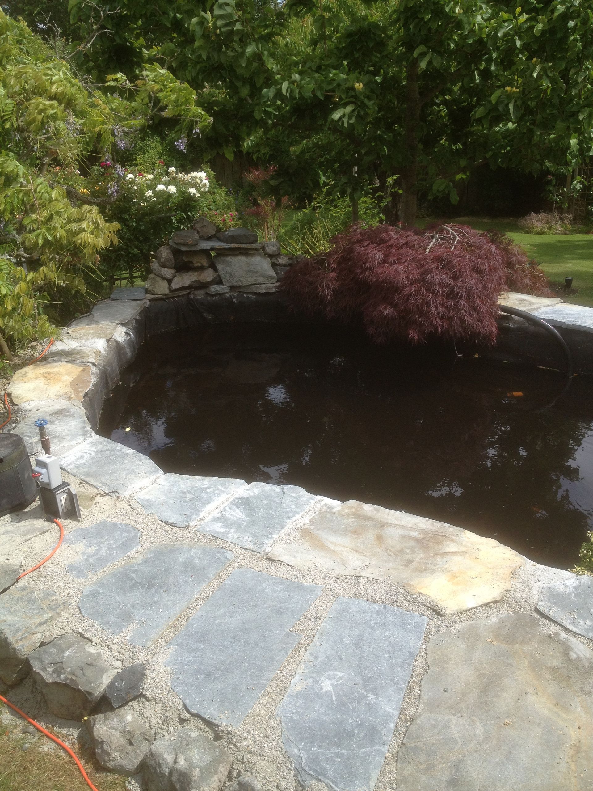 A pond with rock platform installed by the pond contractor at Larix landscape