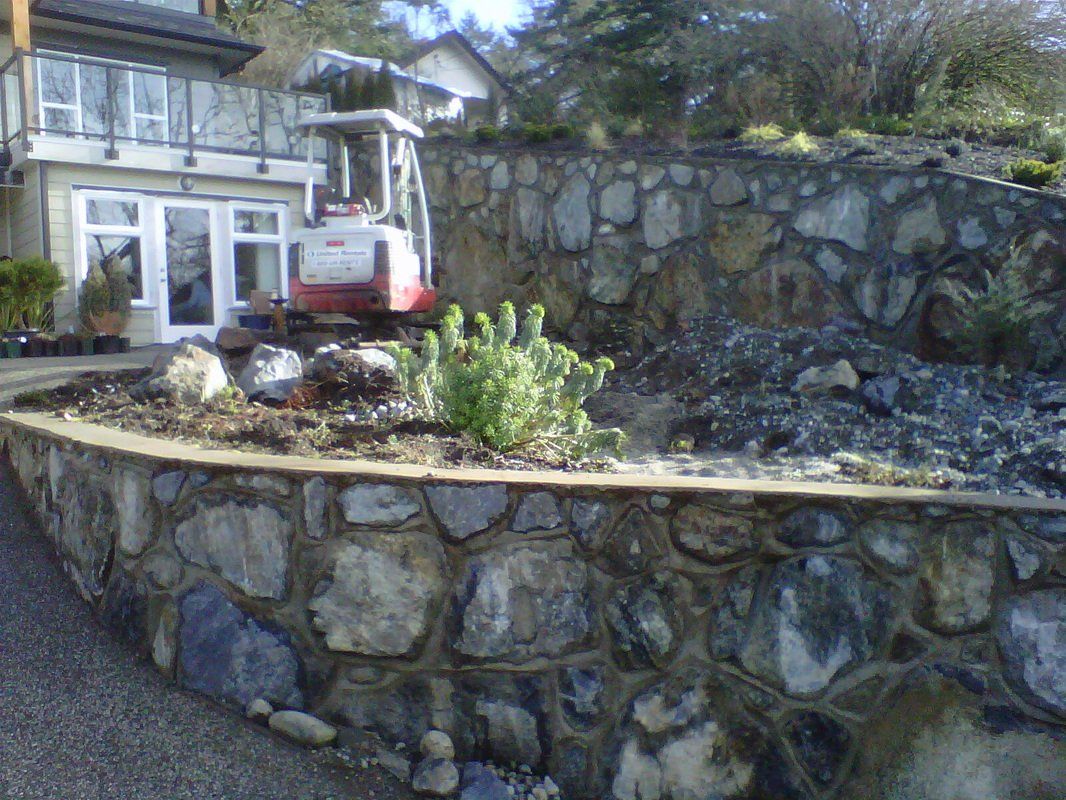 Two retaining walls in front of driveway with residential home in the background