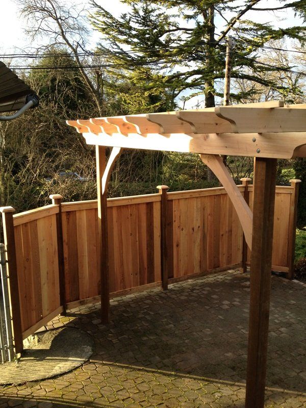 Wooden pergola and fence installed over paved patio for Victoria BC home by Larix Landscape
