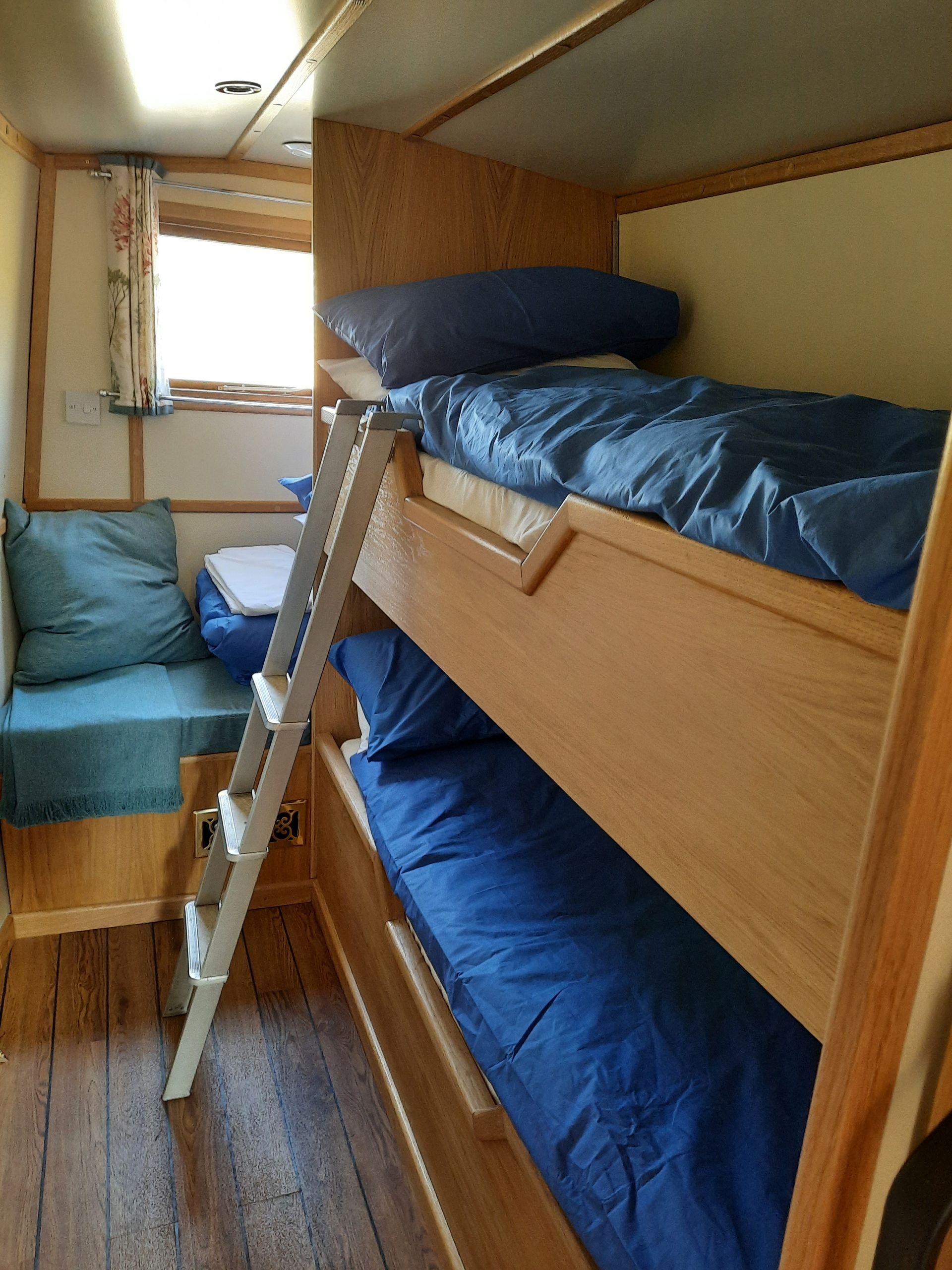 A bunk bed with blue sheets and a ladder