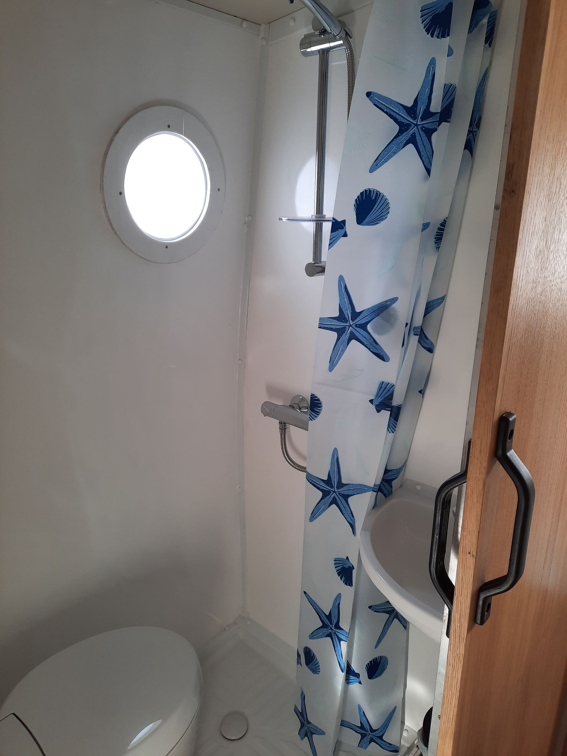 A bathroom with a toilet , sink , shower and starfish shower curtain.