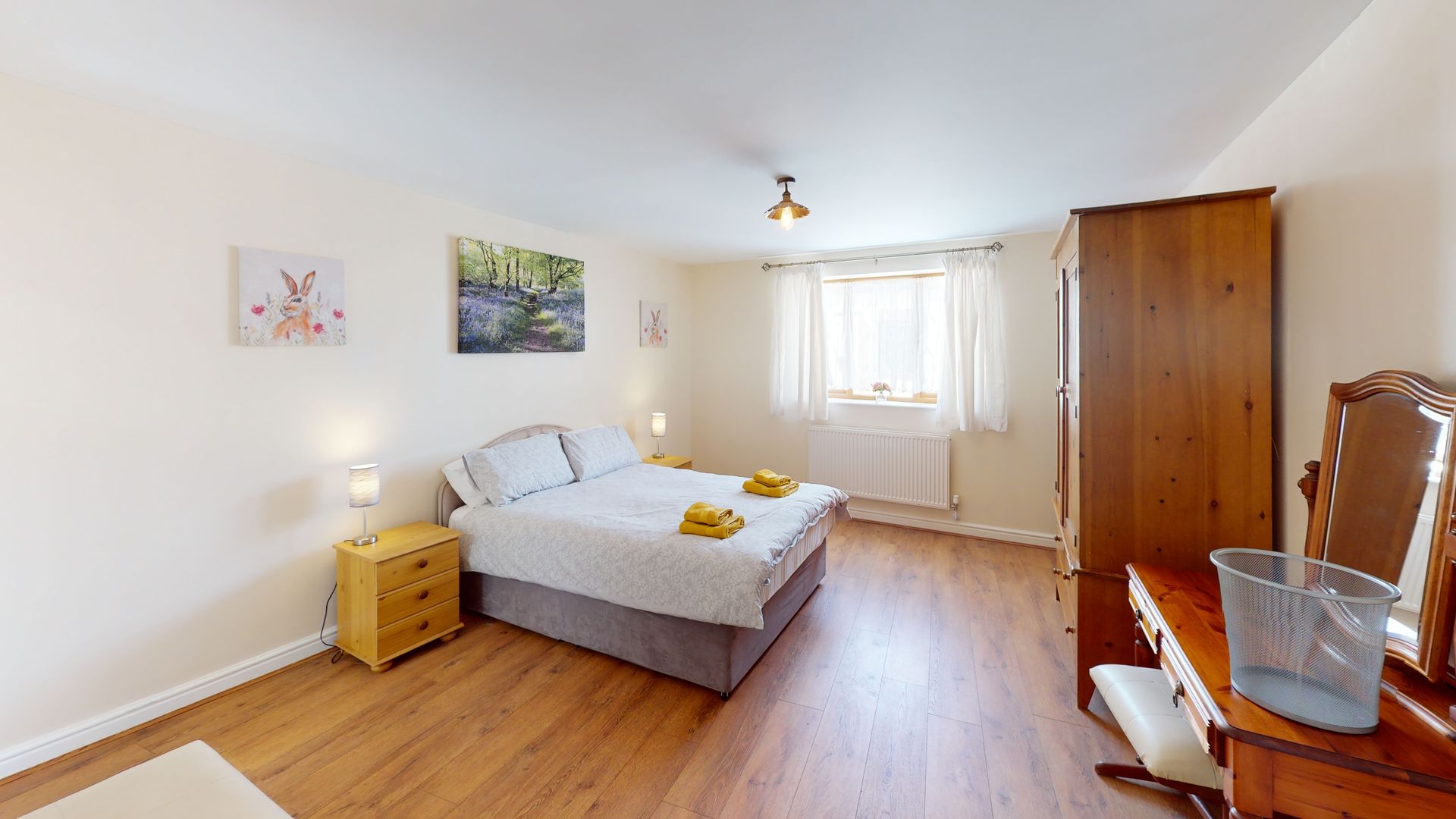 A bedroom with a bed , dresser , nightstand and mirror.