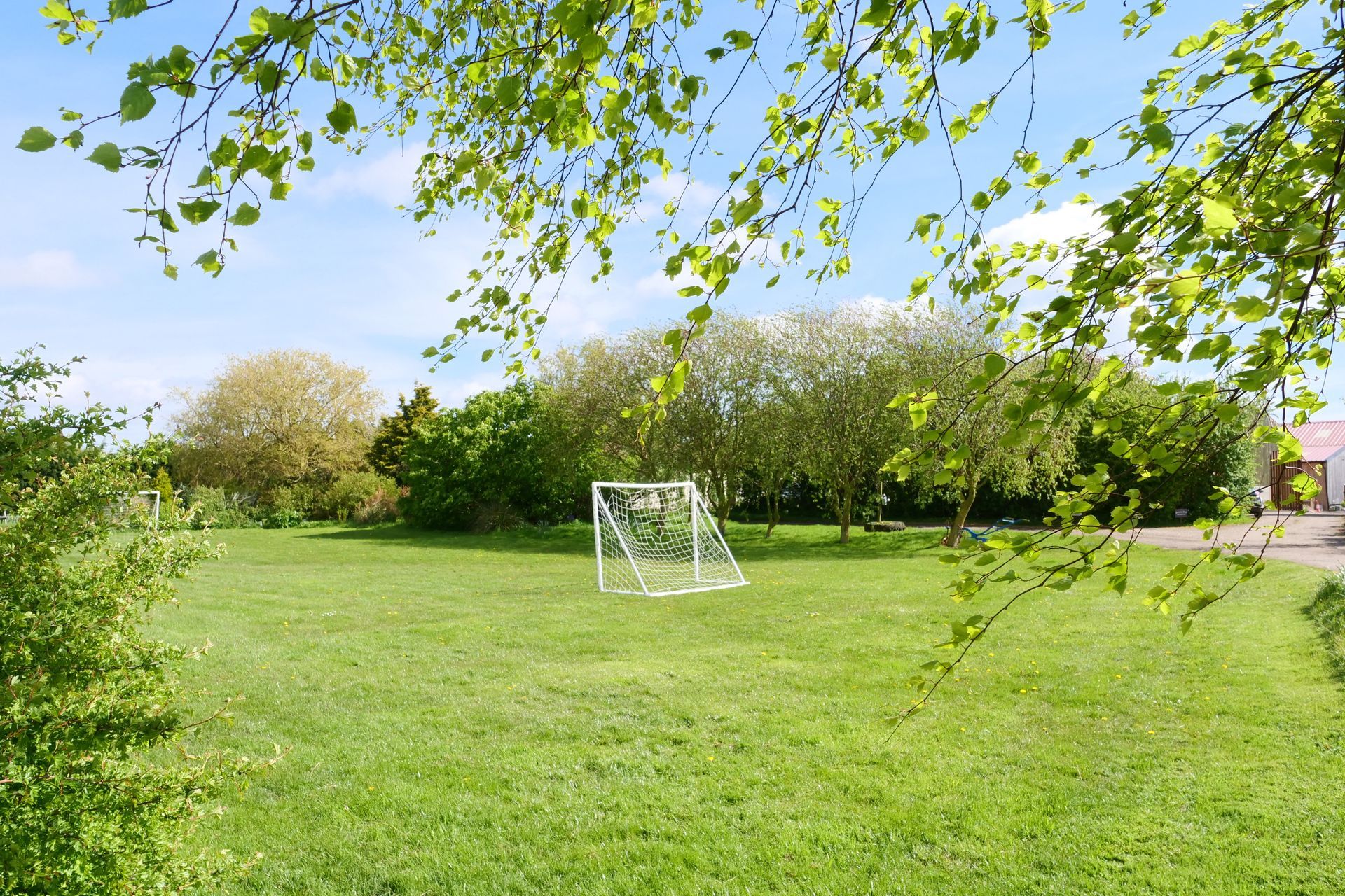 A soccer goal is in the middle of a lush green field