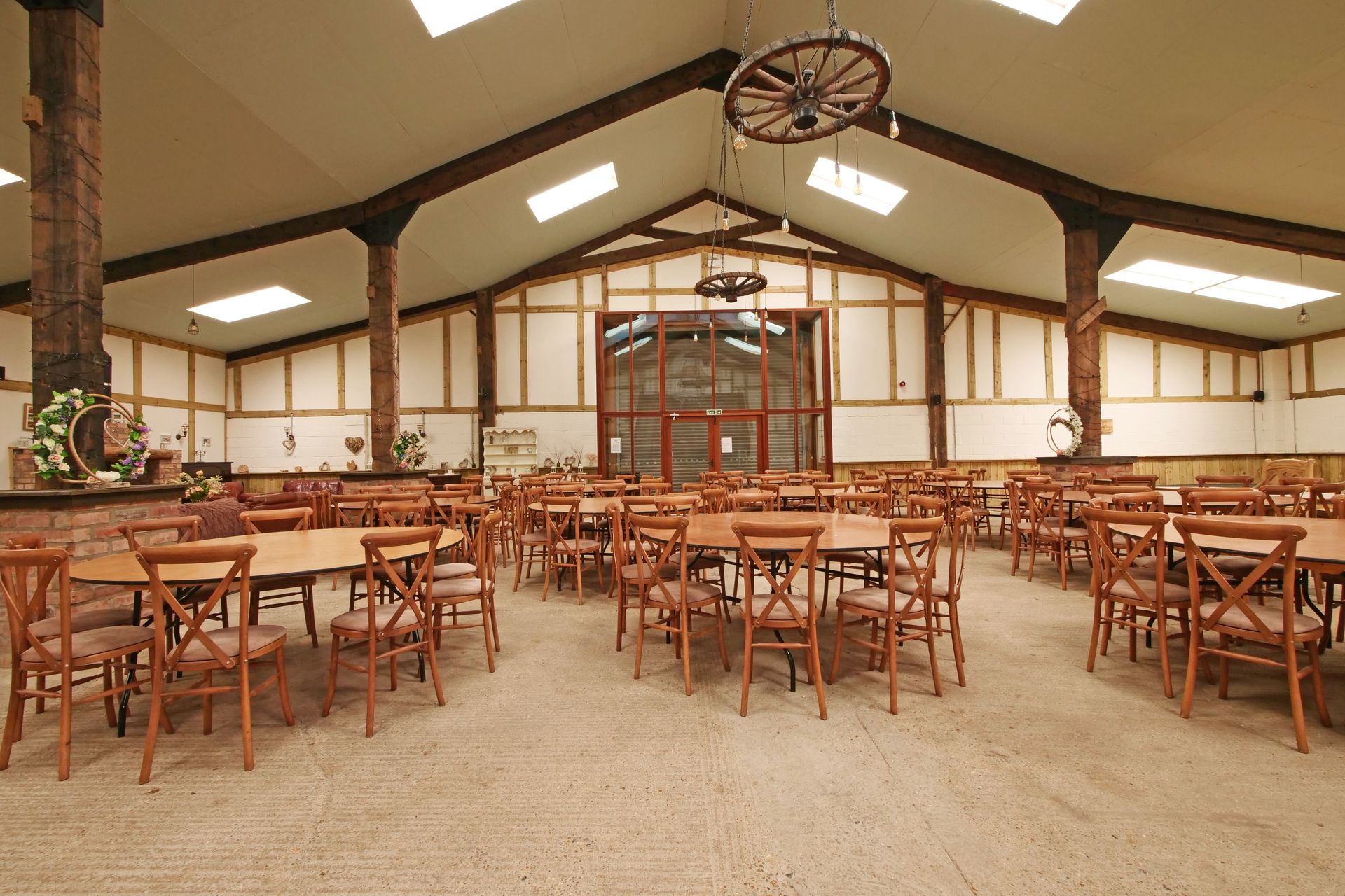 A large room with tables and chairs and a wagon wheel hanging from the ceiling
