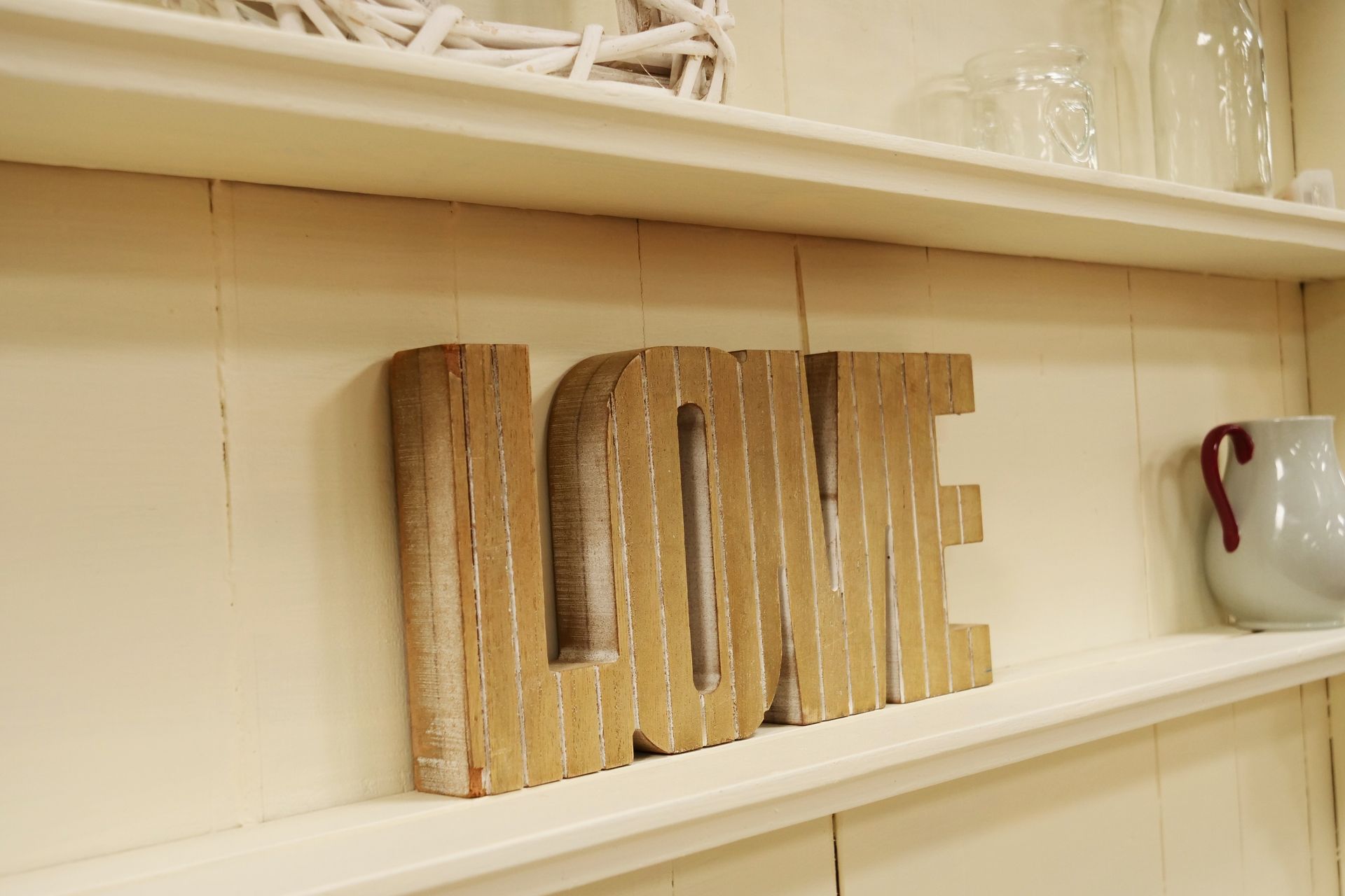 A wooden sign on a shelf that says love