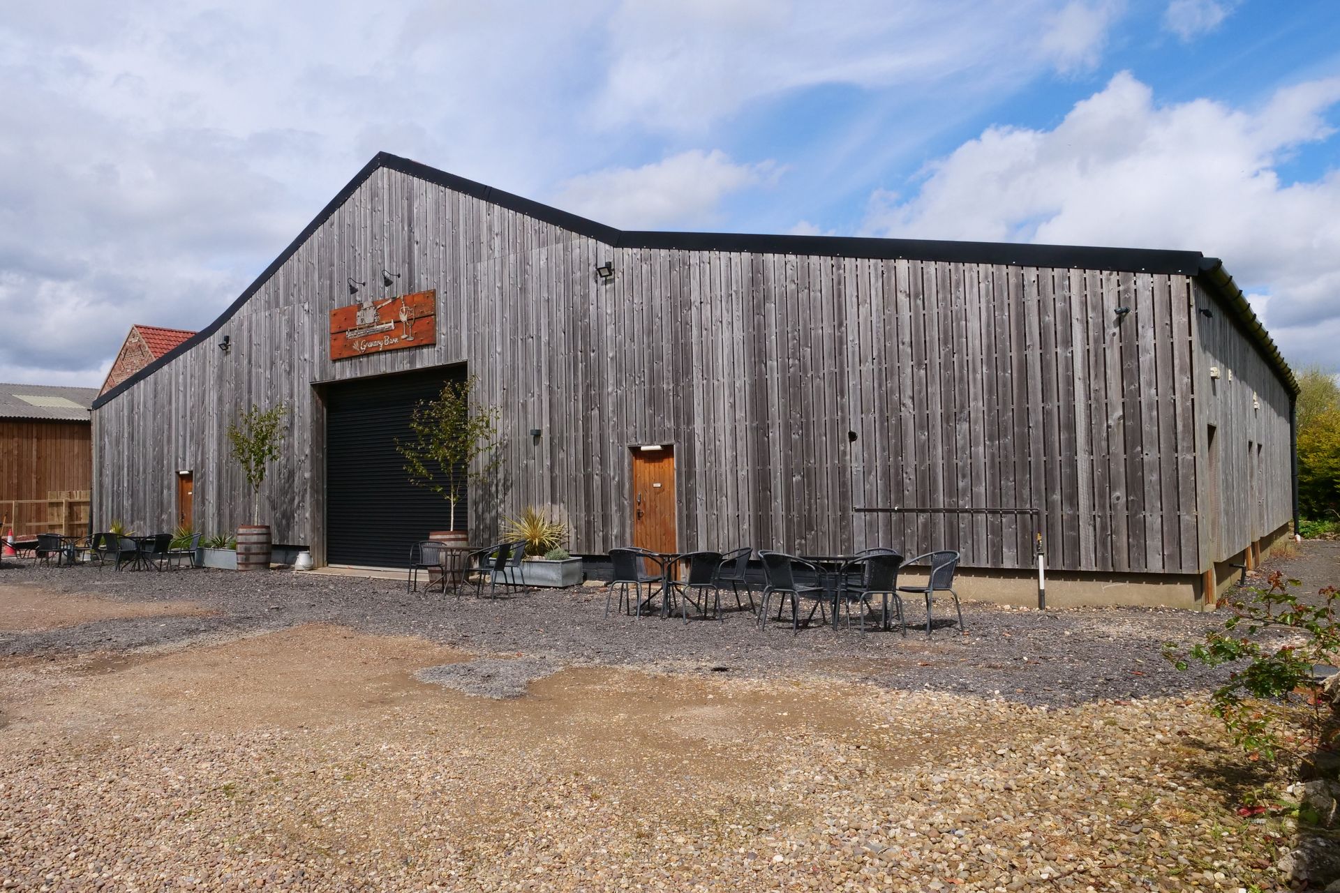 A large wooden building with a black door and a lot of gravel in front of it.
