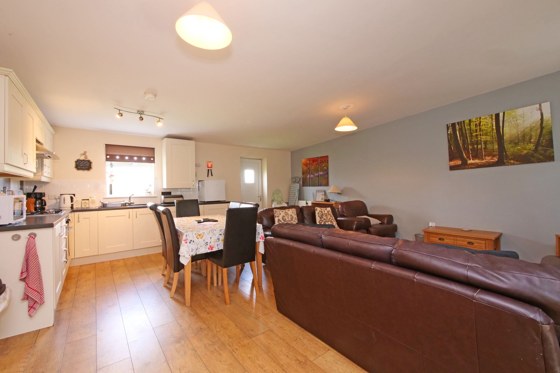 A living room with a couch , table , chairs and a kitchen.