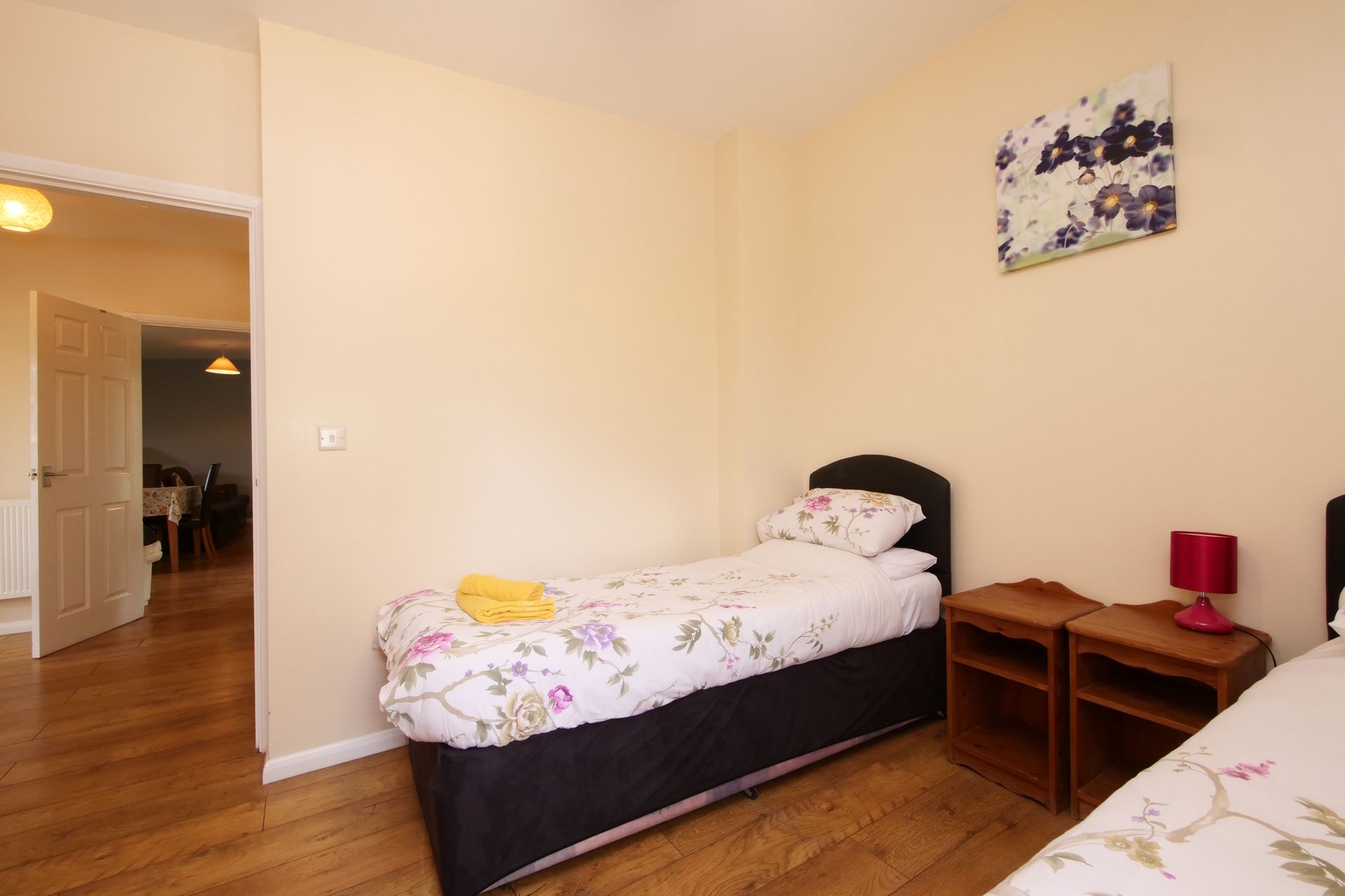 A bedroom with two beds , two nightstands and a painting on the wall.