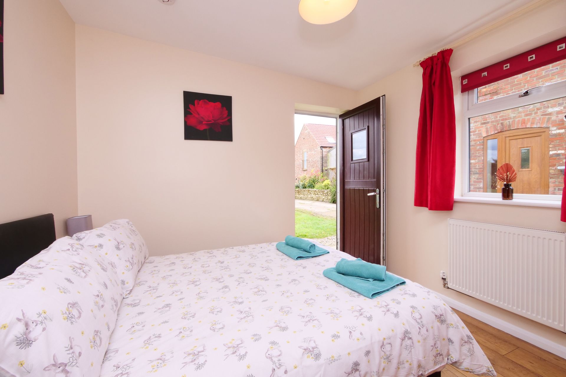A bedroom with a bed and a window with red curtains