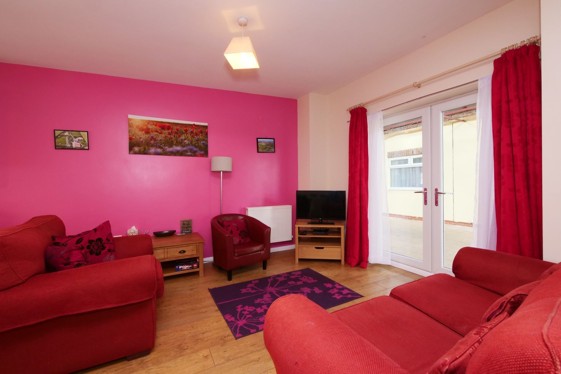 A living room with red furniture and pink walls.