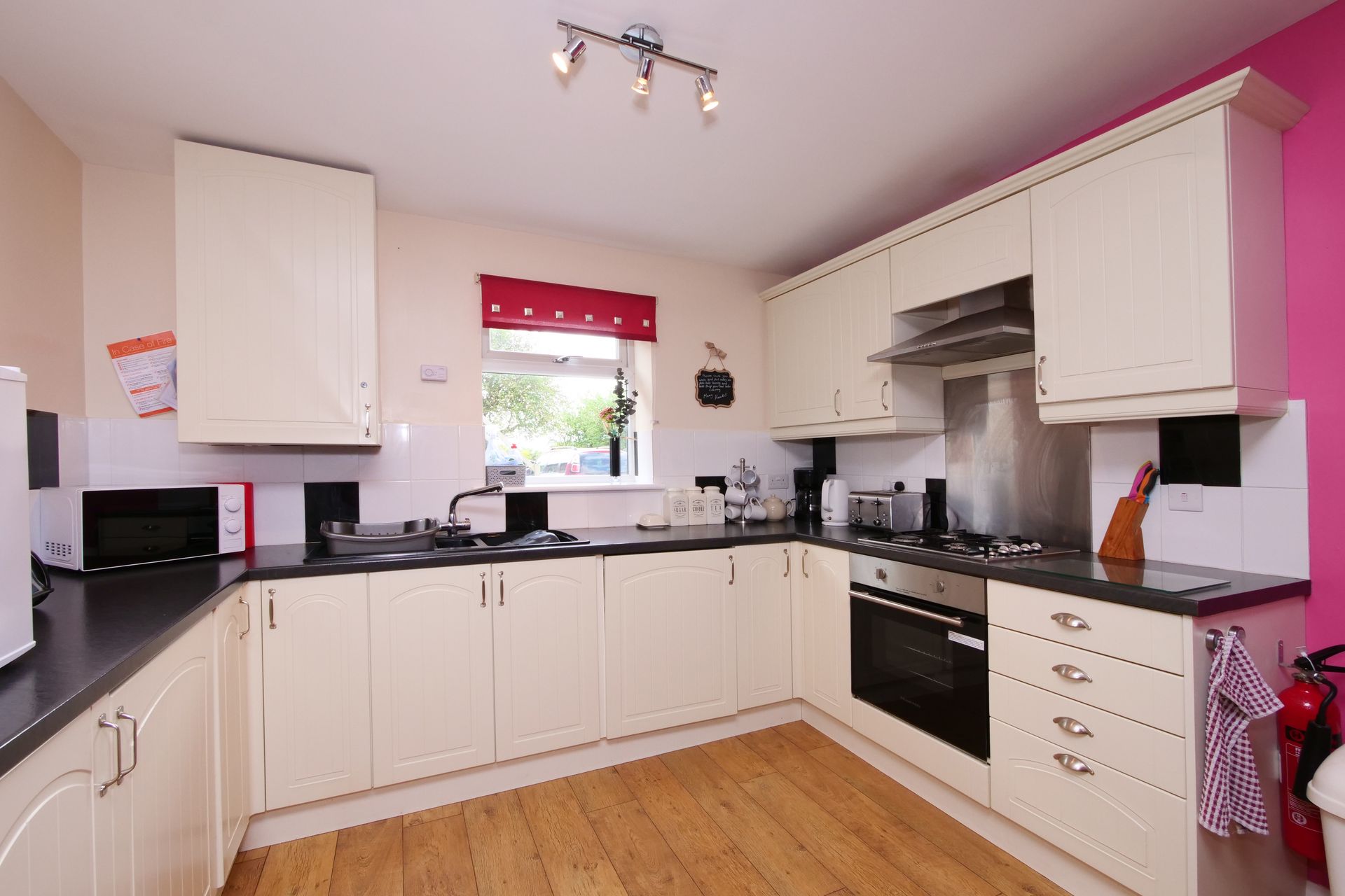 A kitchen with white cabinets and a pink wall