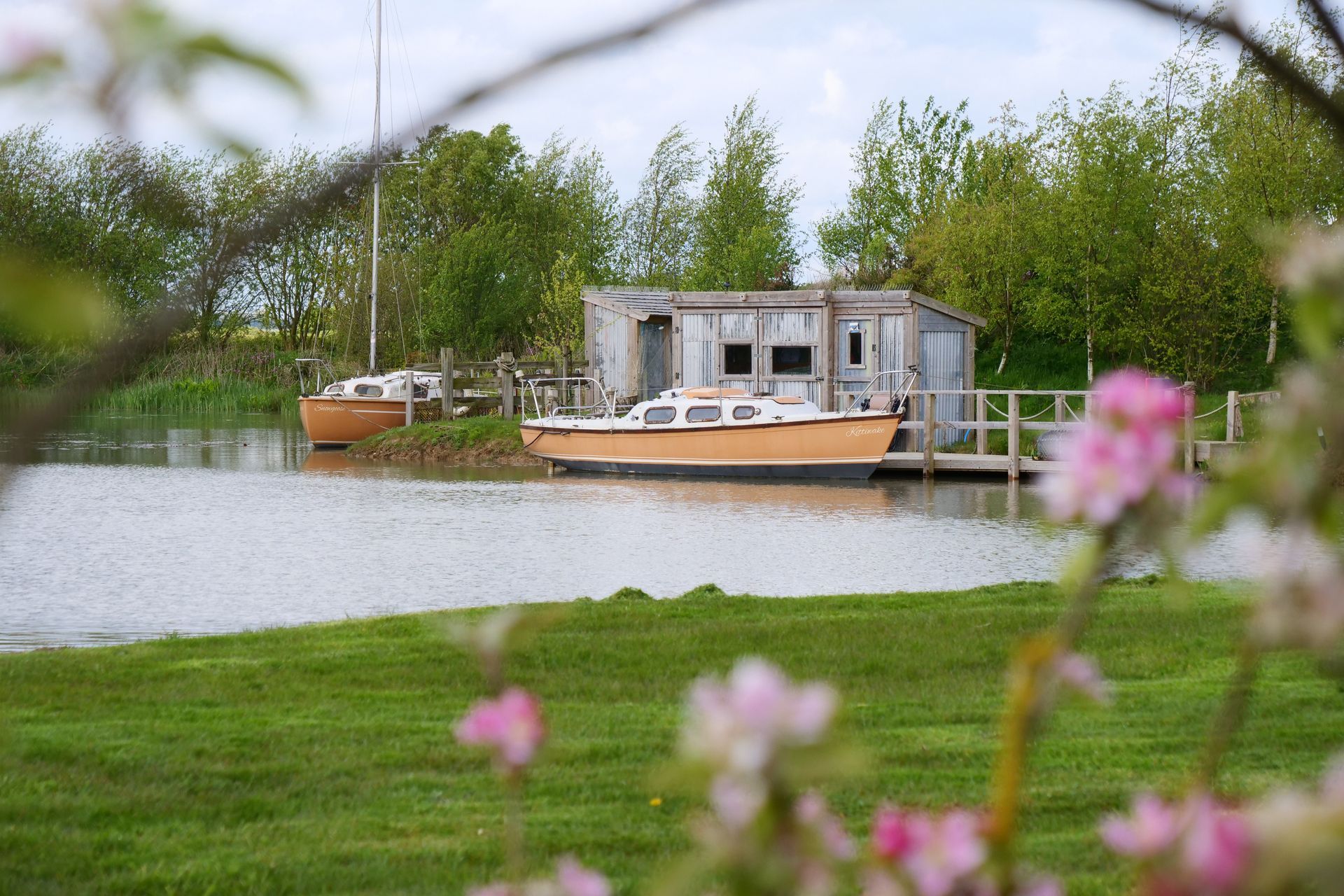 A boat is floating on top of a body of water next to a house.
