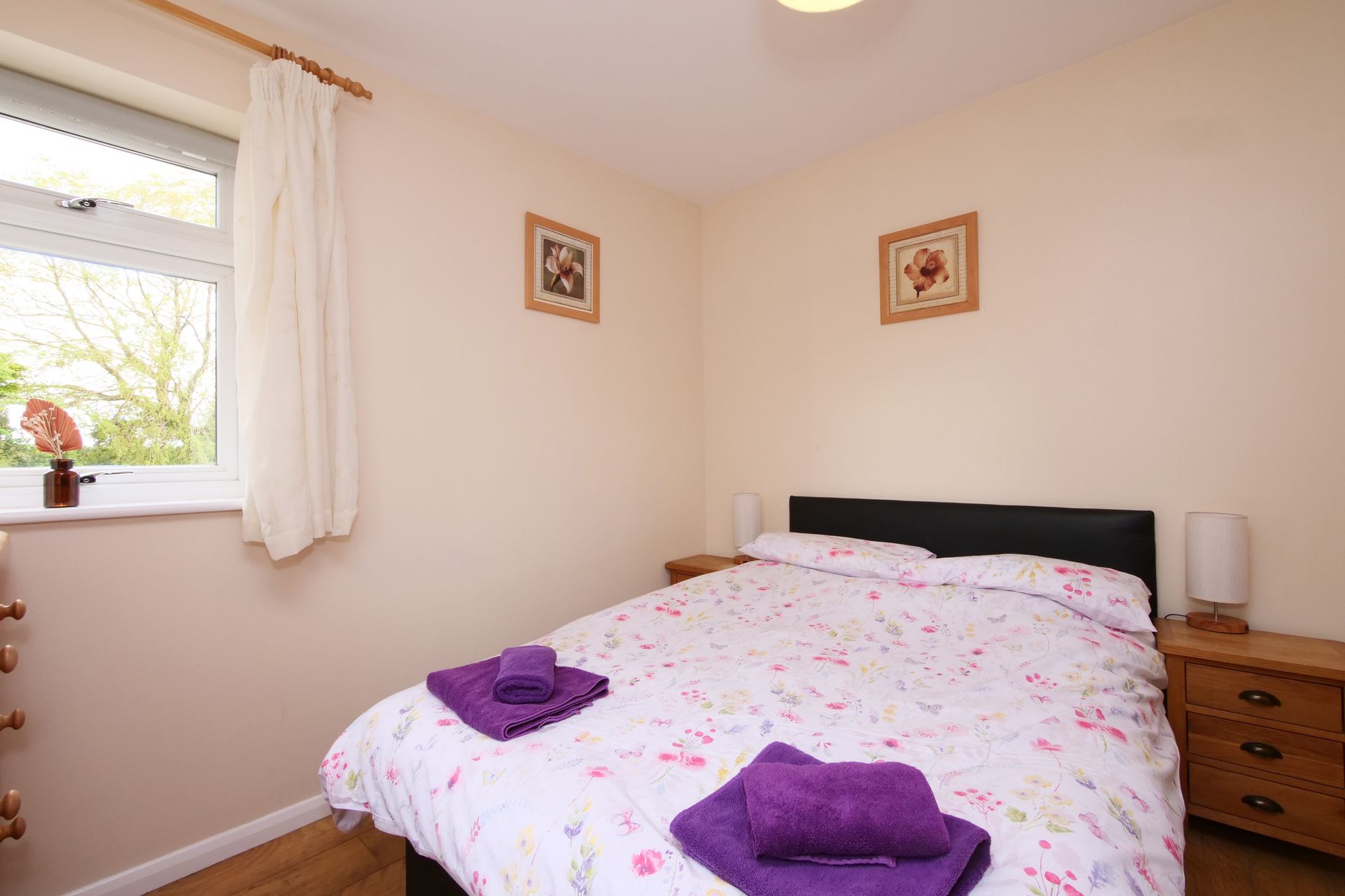 A bedroom with a bed , two nightstands , and a window.