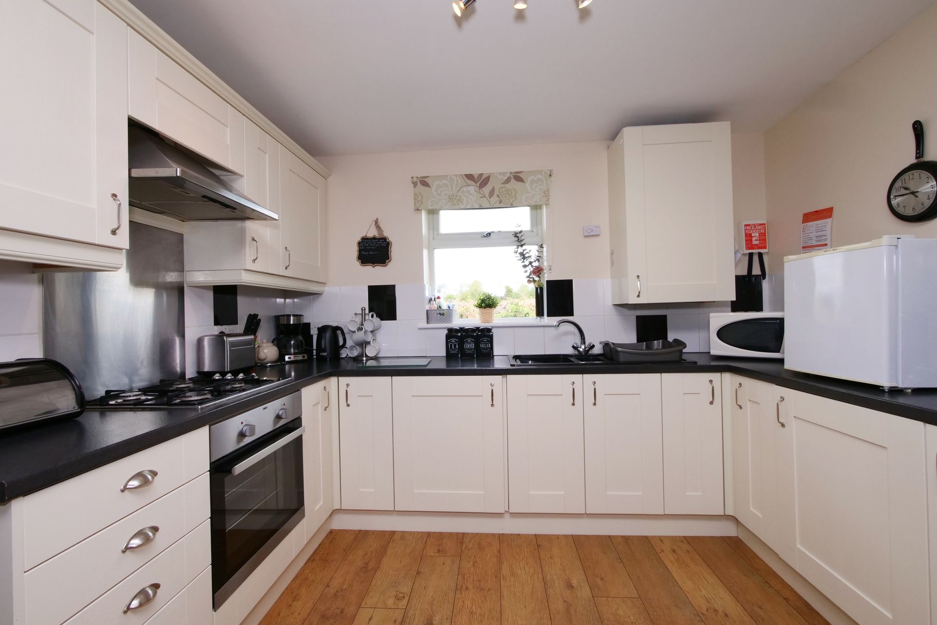 A kitchen with white cabinets and wooden floors