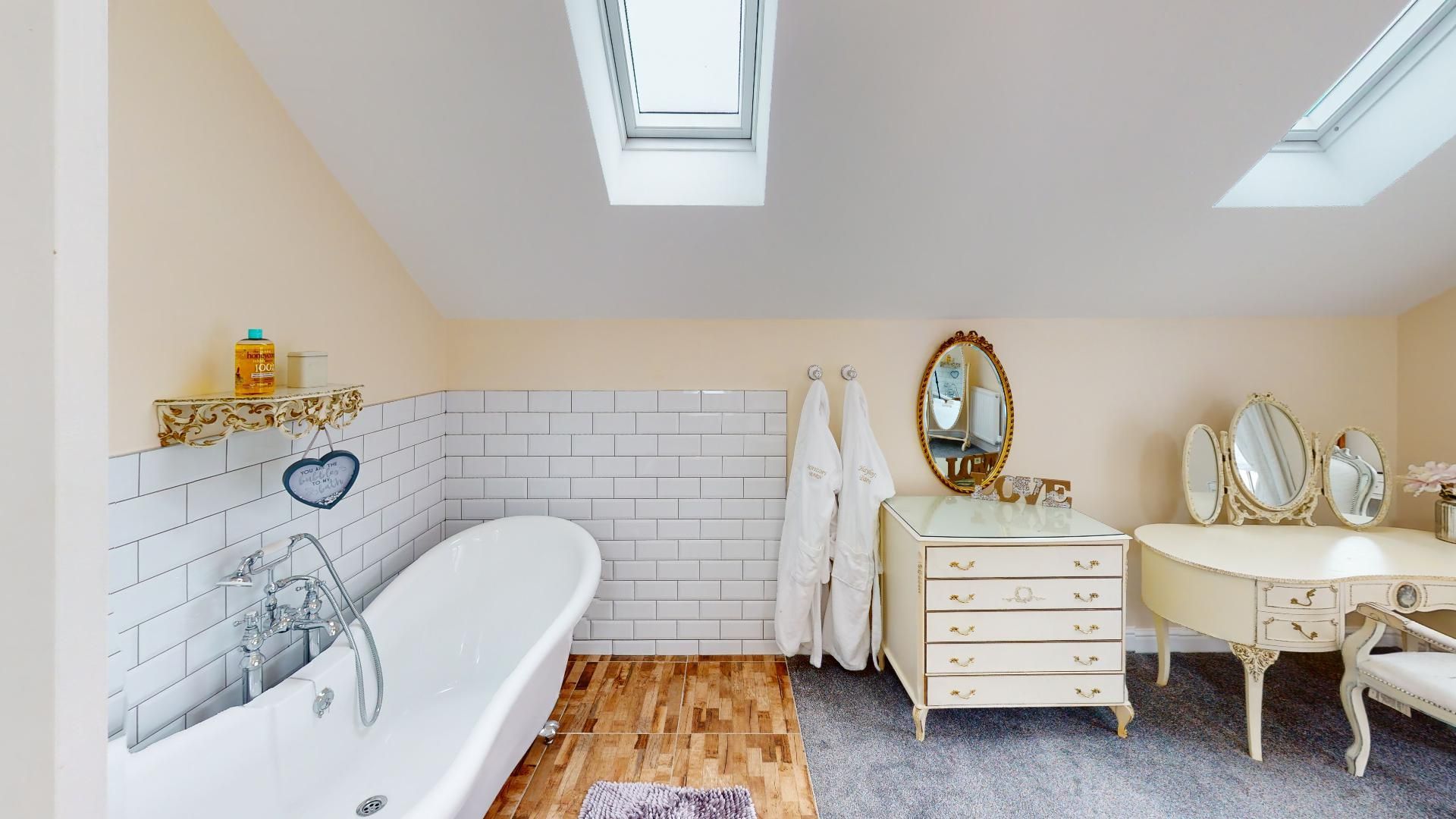 A bathroom with a bathtub , dresser , mirror and skylight.