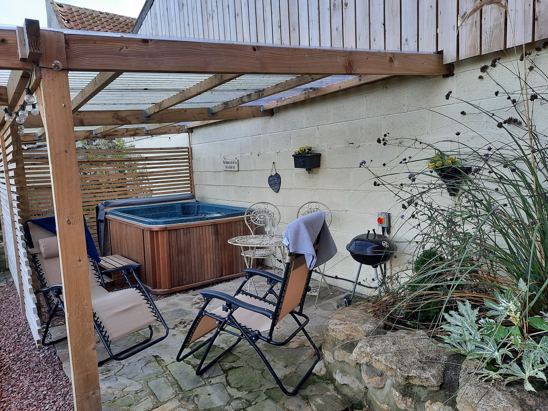 There is a hot tub in the backyard under a pergola.