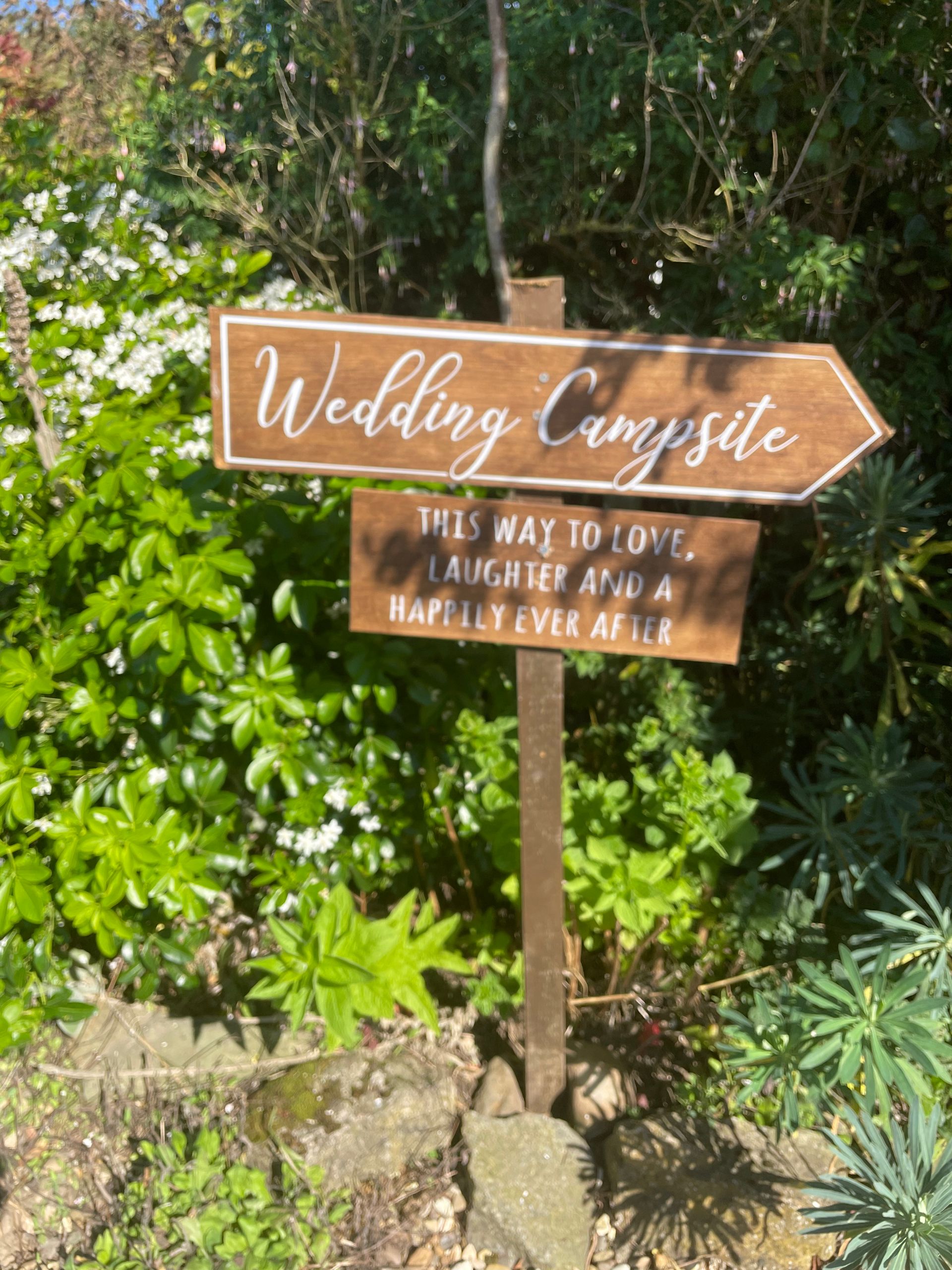 A wooden sign pointing to a wedding campsite