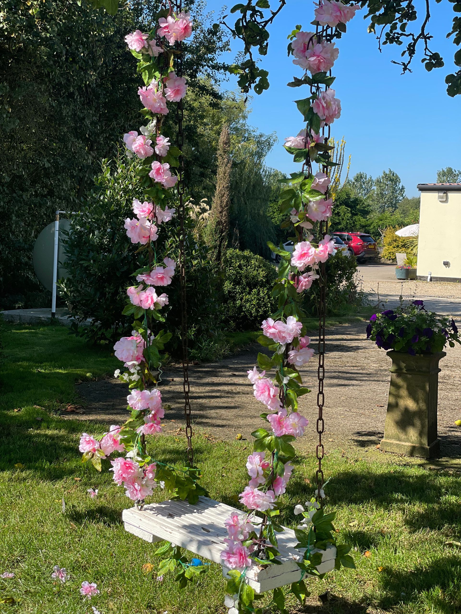 A white swing with pink flowers hanging from it