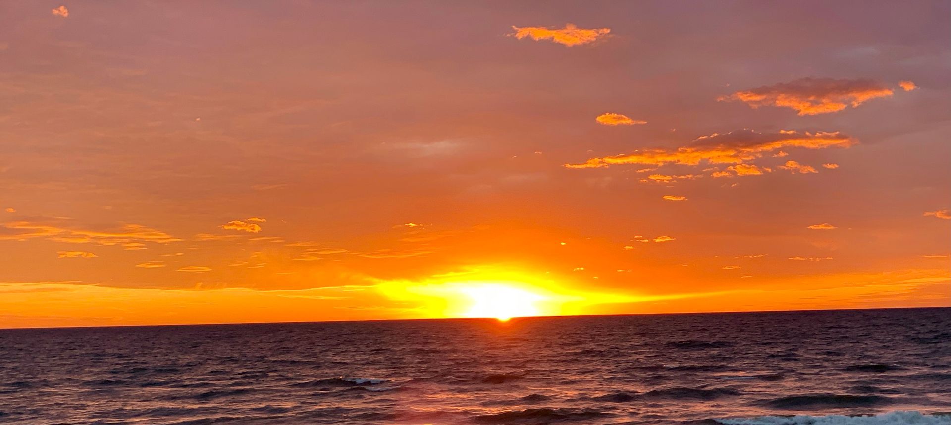 A man and a woman are sitting on a boat looking at the ocean.