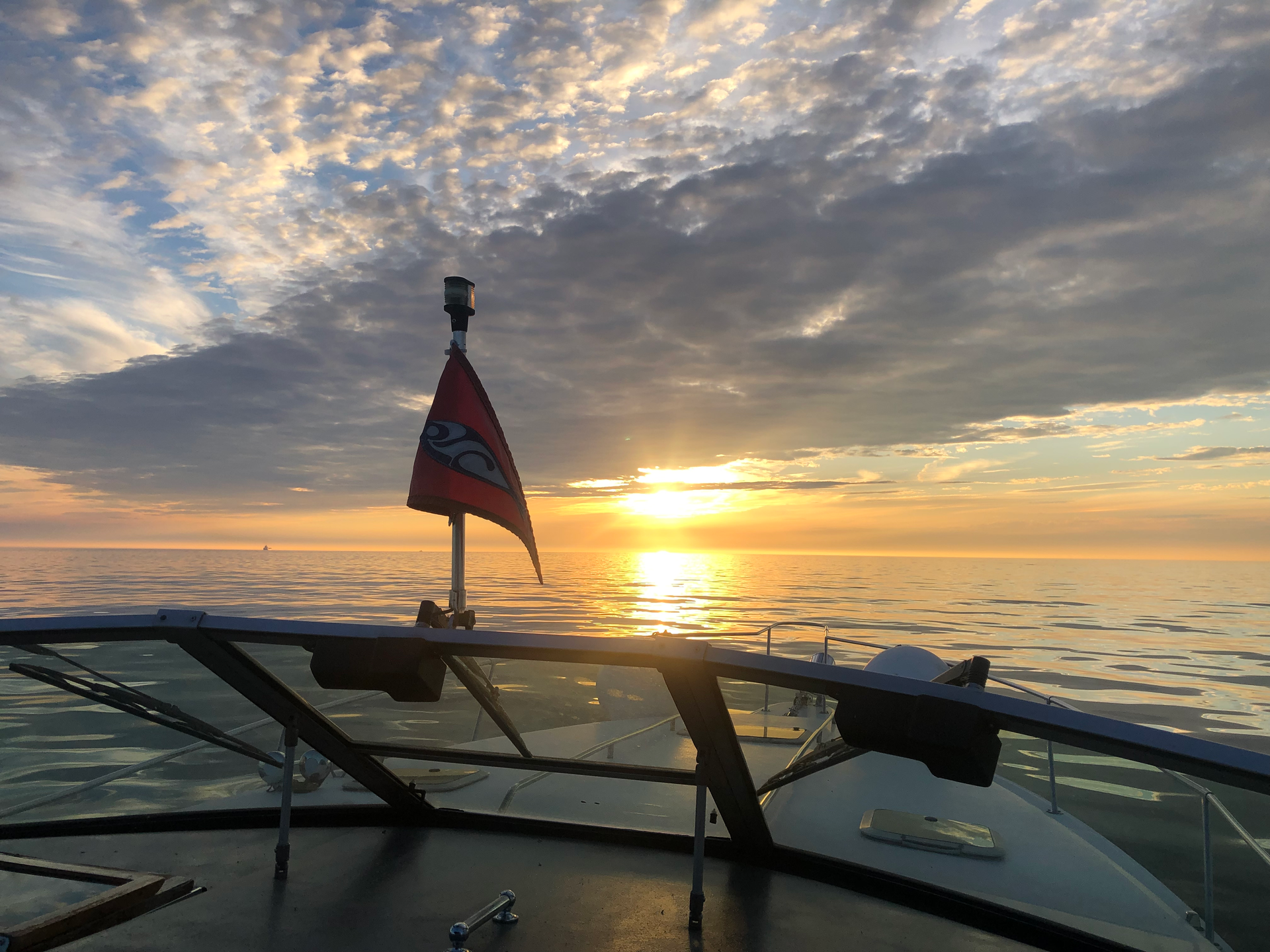 A sailboat is floating on top of a body of water at sunset.