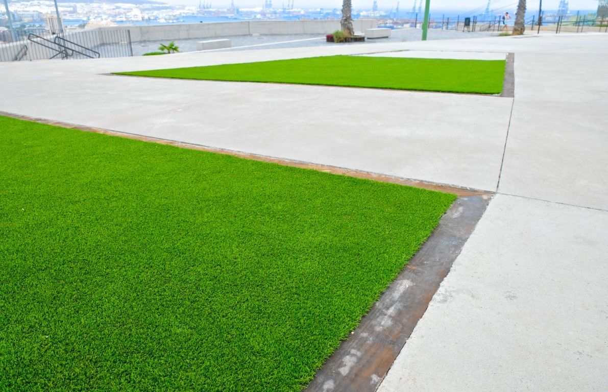 Rectangular patches of bright green artificial turf embedded in a light gray concrete plaza.