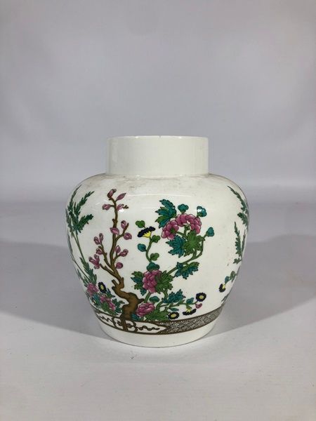 Tarro de porcelana blanca con coloridos diseños florales y de pájaros.