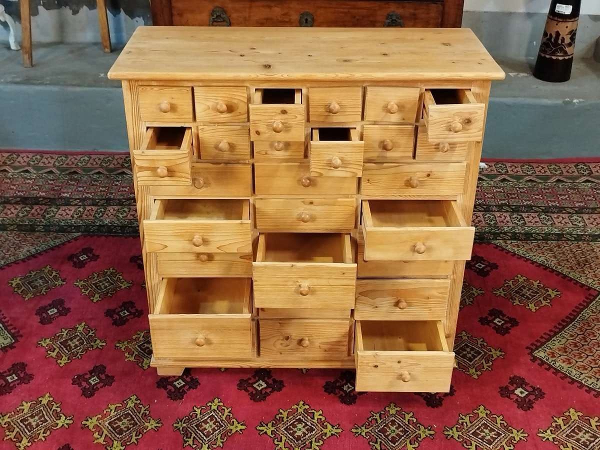 Cómoda de madera con múltiples cajones, situada sobre una alfombra estampada.