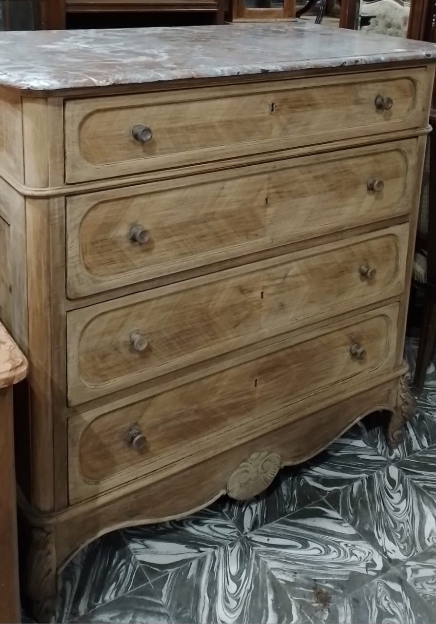 Cómoda de madera con cuatro cajones, tapa de mármol y talla decorativa.