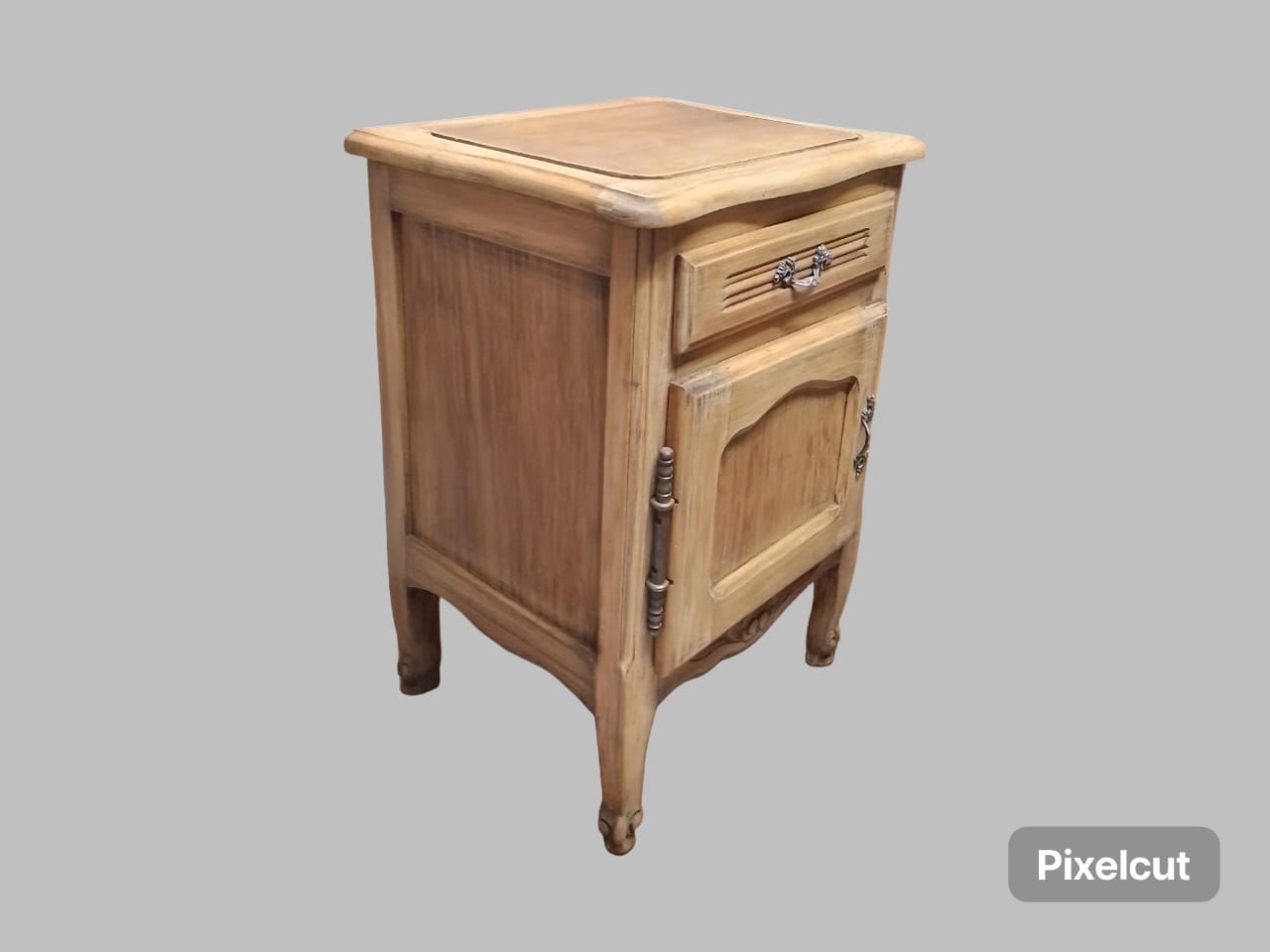 Mesita de noche de madera con cajón y puerta, tallas ornamentadas, acabado marrón claro.