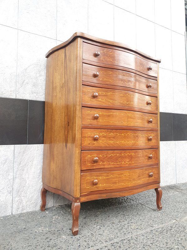 Cómoda de madera de estilo vintage con frente curvo y pequeños tiradores de pomo. Patas en ángulo.