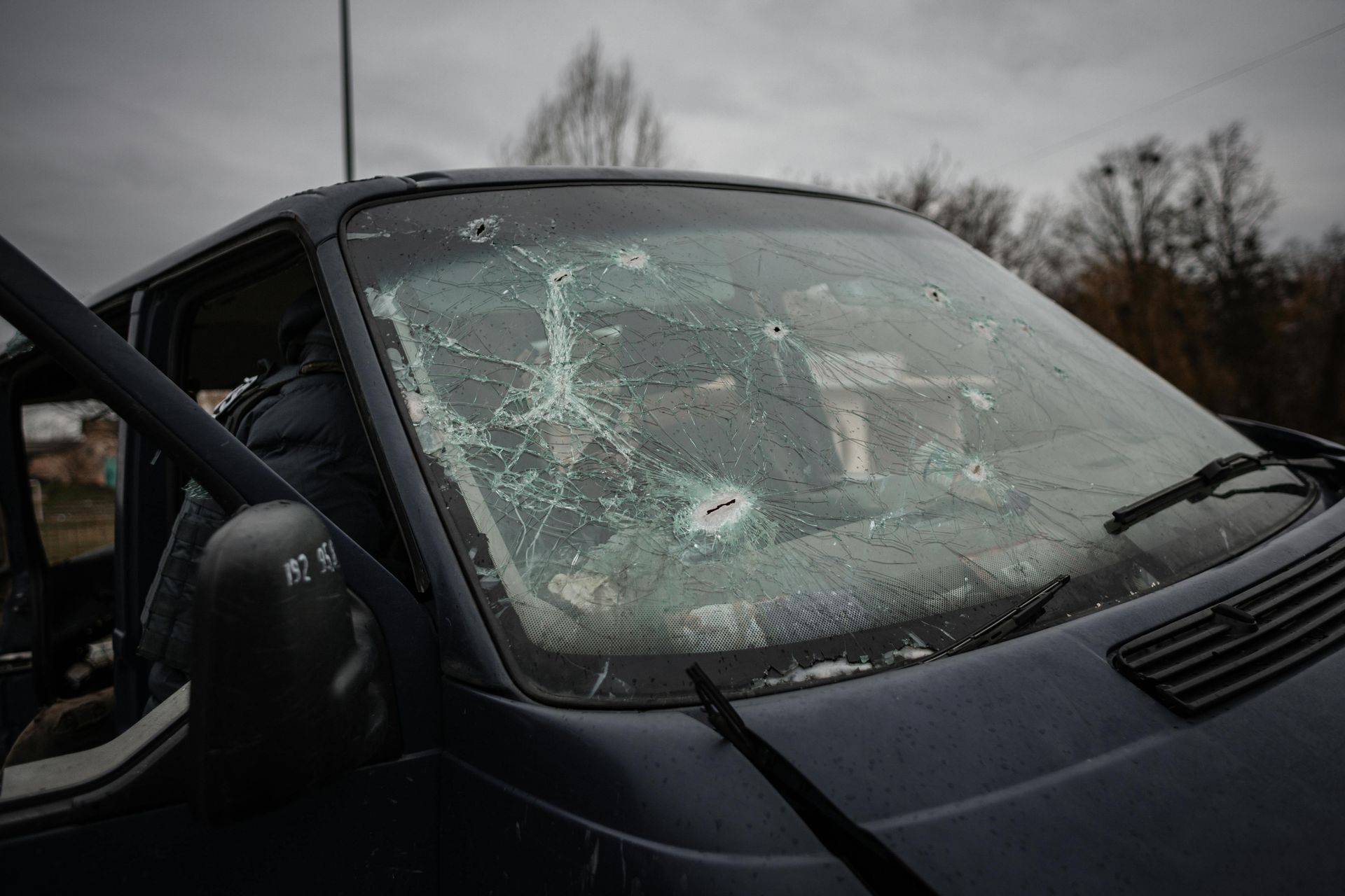 Van windshield shattered with multiple bullet holes.