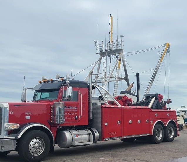A man is working on the hood of a red truck
