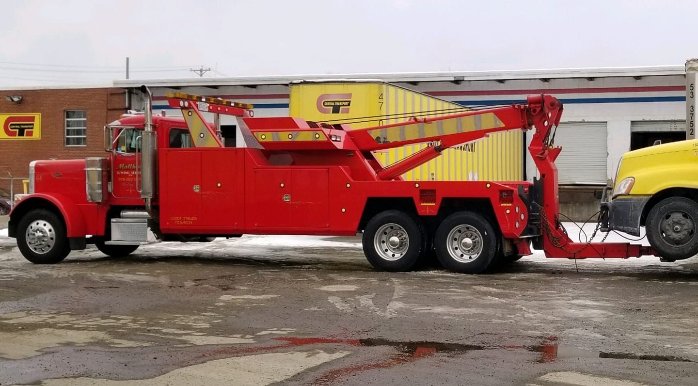 A red car is being towed by a tow truck