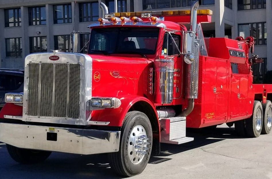 A red truck is parked in a garage with its lights on
