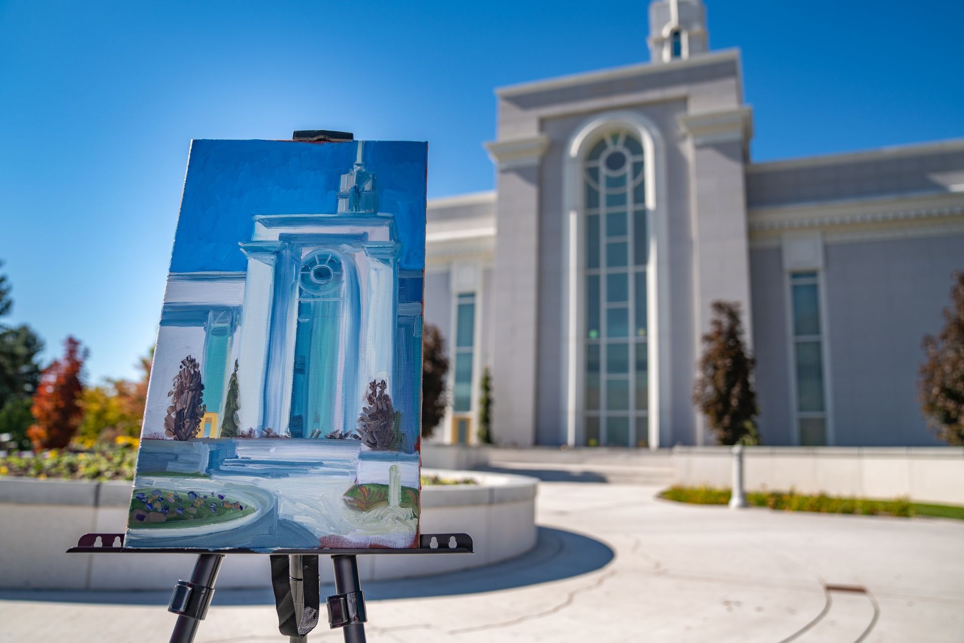 A painting is sitting on an easel in front of a building.