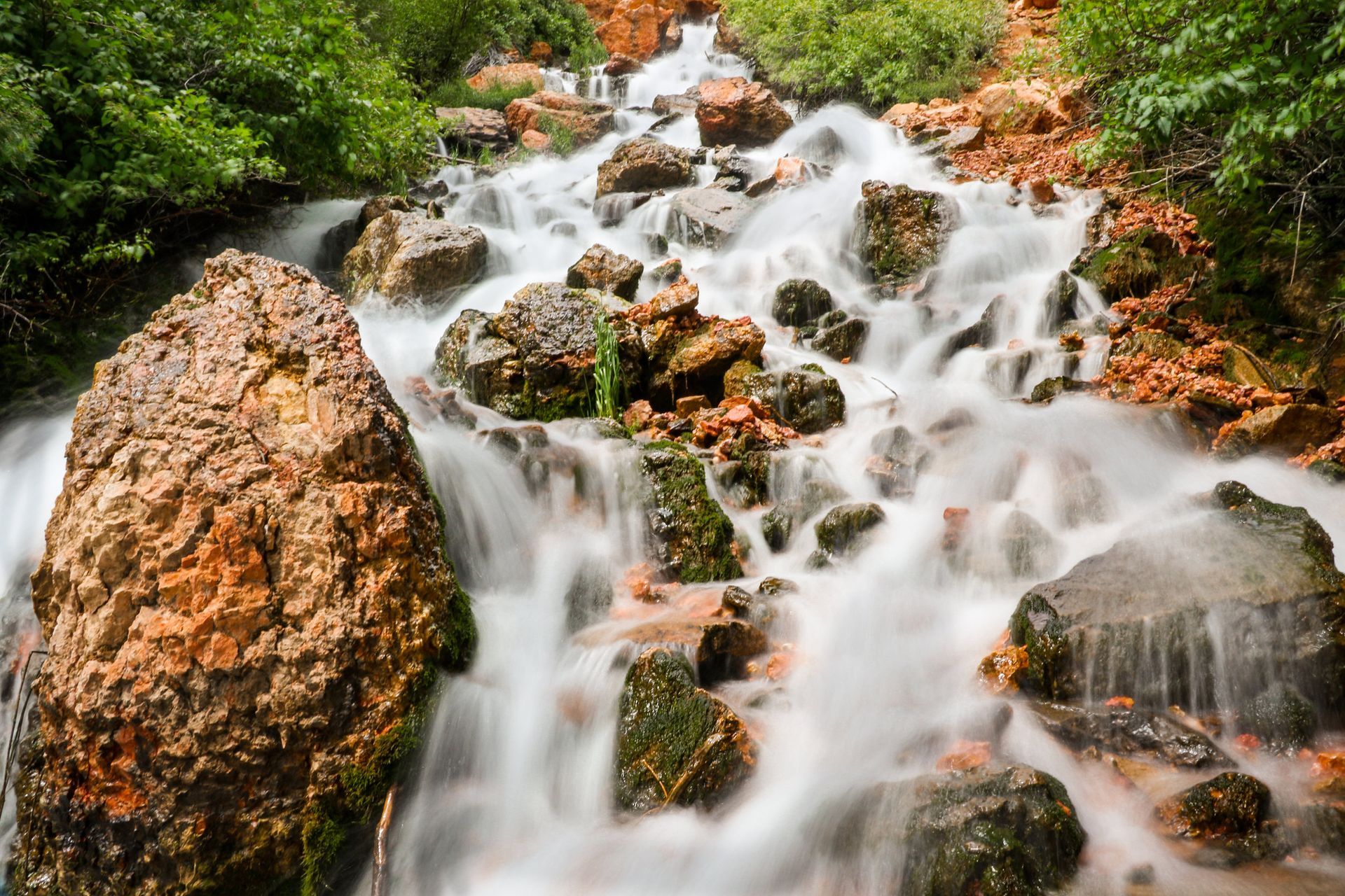 A waterfall is surrounded by rocks and trees in a forest.