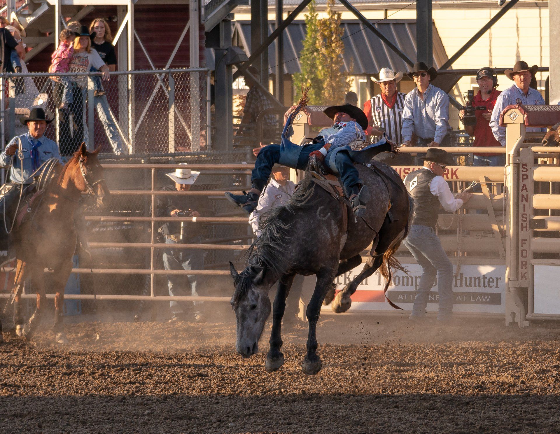 A man riding a bucking horse in a rodeo arena